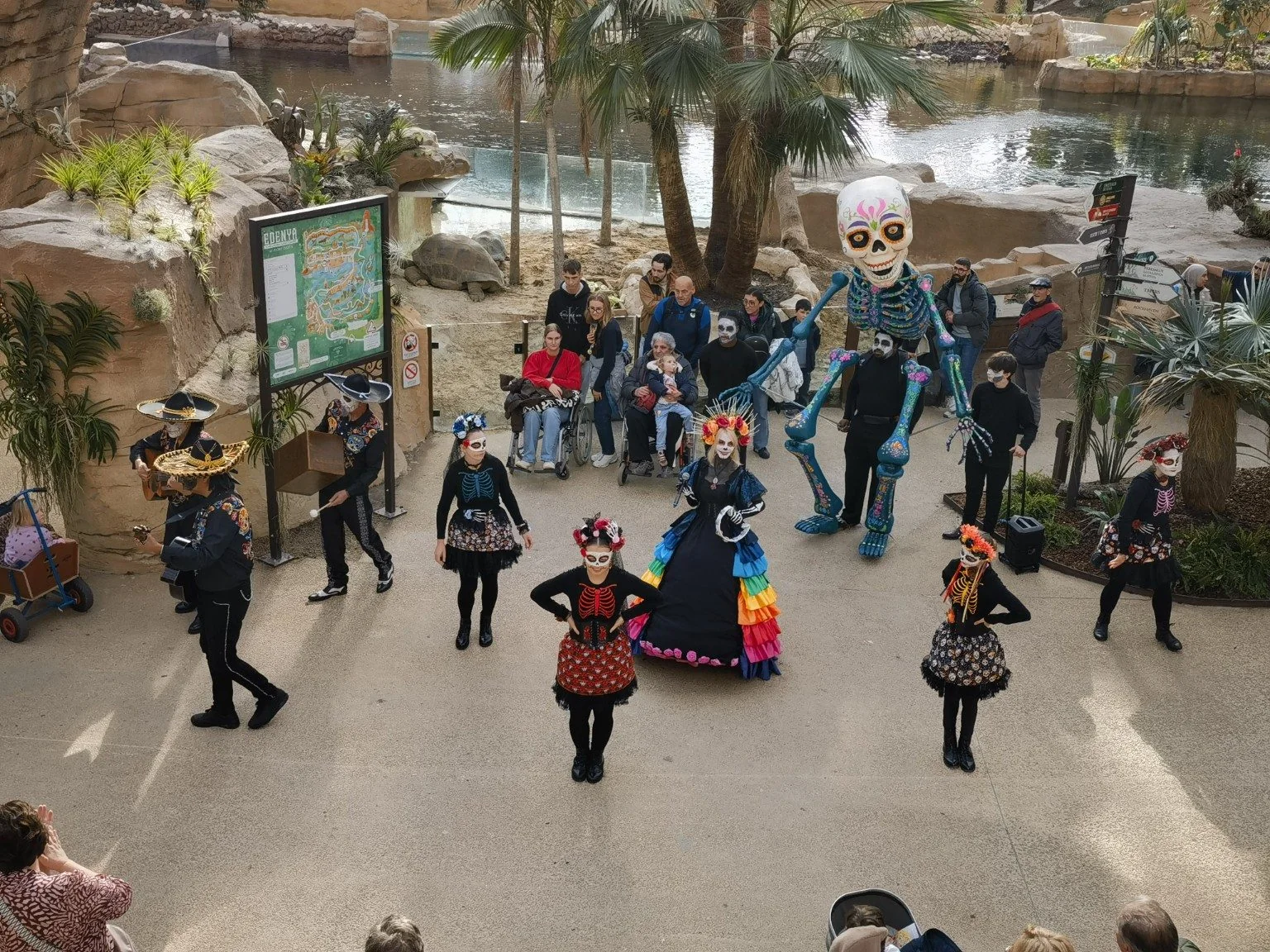 从高处俯拍 Viva Los Muertos 的彩裙演员、骷髅装舞者与巨型骷髅人偶